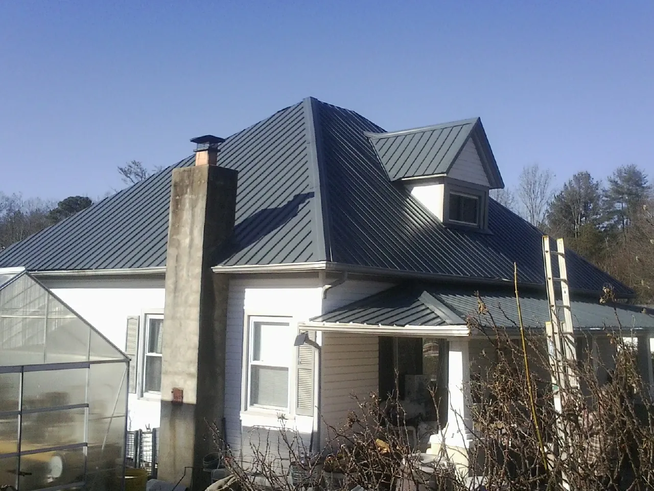 Dark blue standing seam metal roof on a white farmhouse with dormer — Slate & Tile Roof Repair by Roofing Brothers in Essington