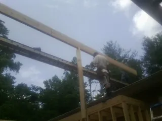 Carpenter setting a ridge beam over a new addition frame — Ice Dam Removal by Roofing Brothers in Essington