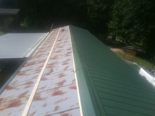 Old rusted panels beside newly installed green metal roofing — Wind Damage Roof Repair by Roofing Brothers in Essington