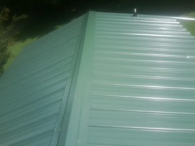 New green metal panels meeting at the ridge of a roof — Flat Roof Repair work by our crew in Essington