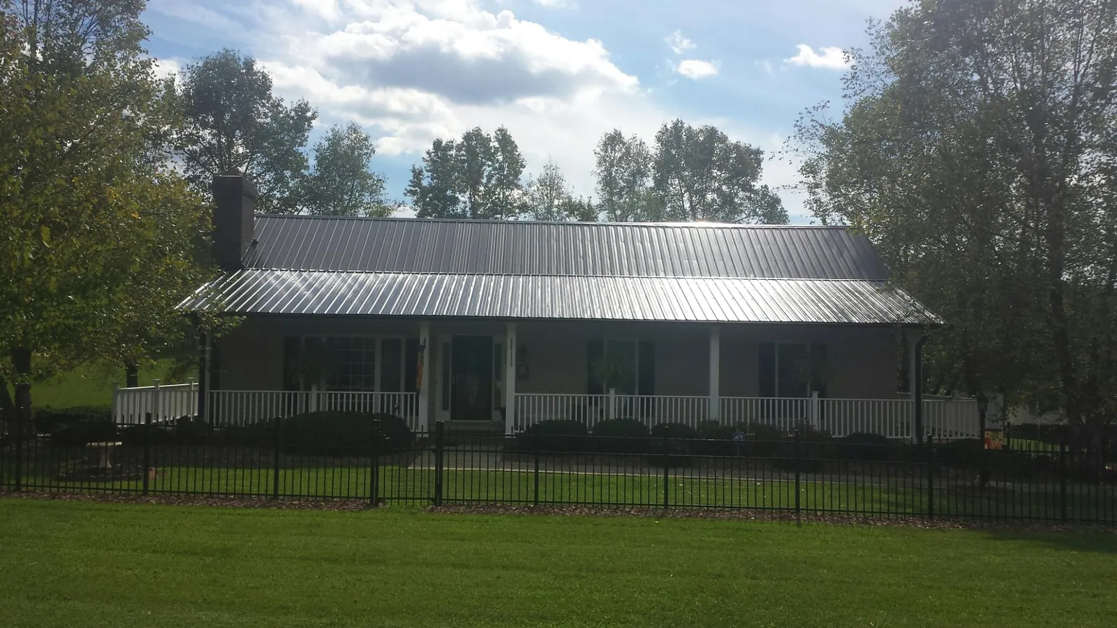Gray metal roof on a brick ranch with a full width front porch — Gutter Guard Installation work by our crew in Essington