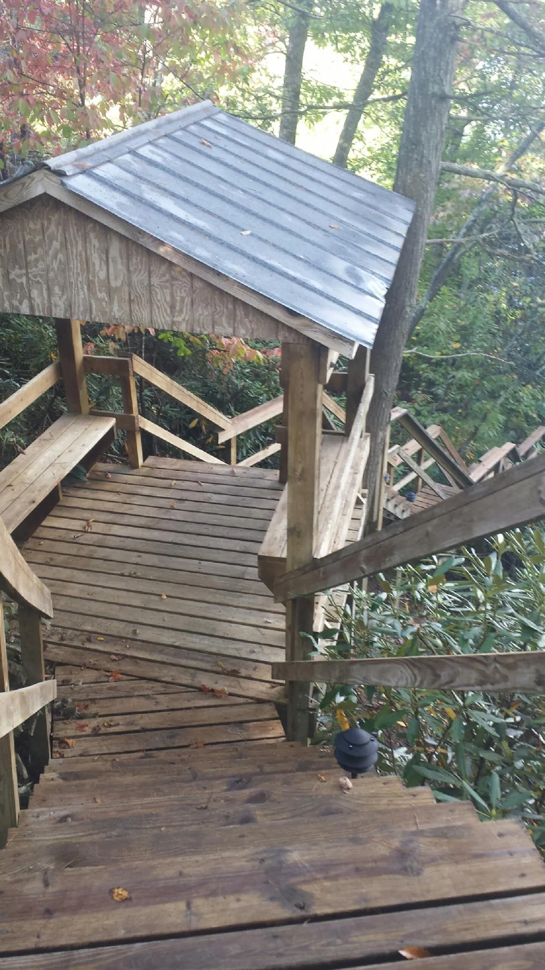 Metal roofed shelter over wooden steps on a wooded walkway — Skylight Repair & Installation work by our crew in Essington