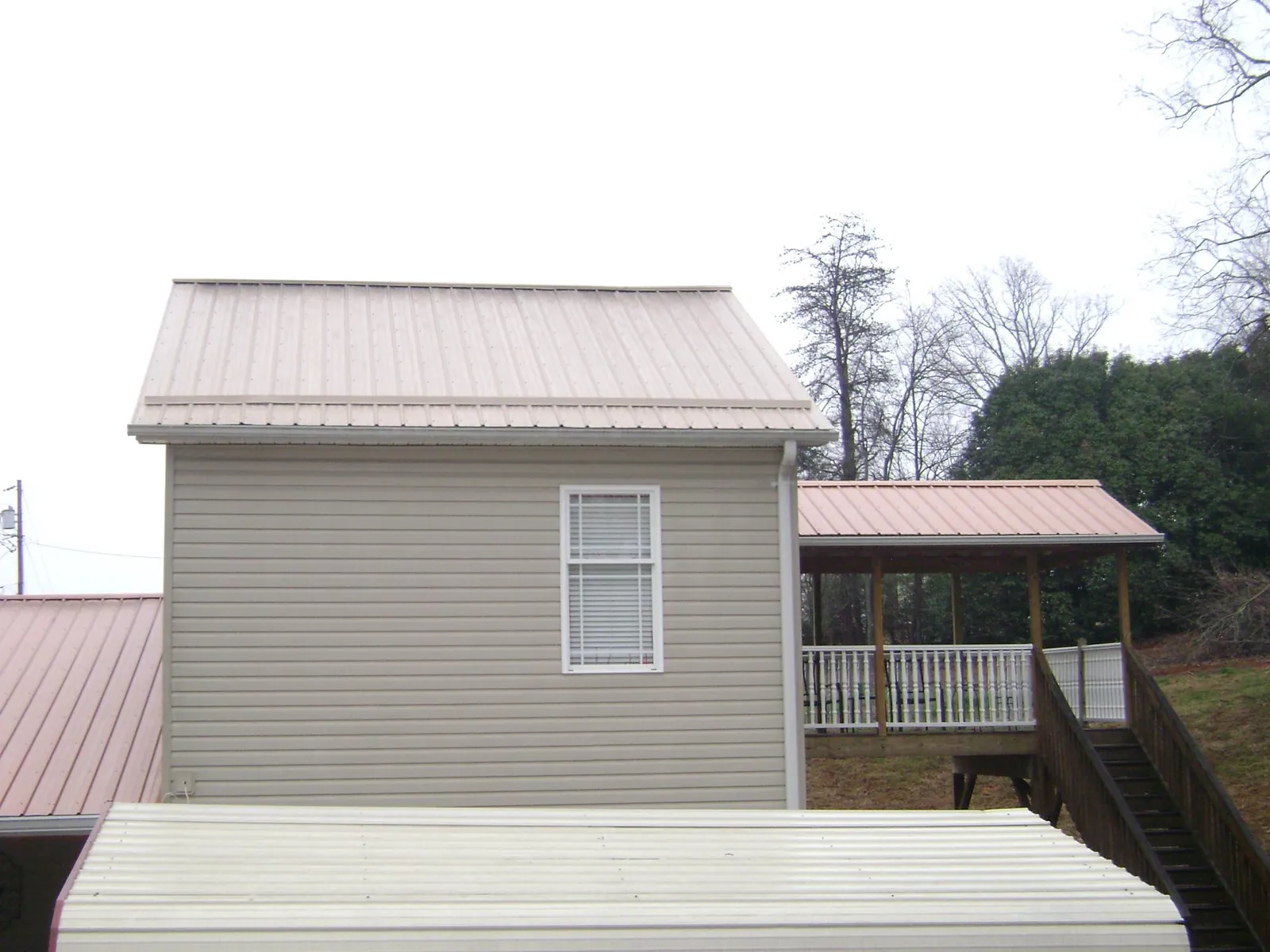 Tan metal roofs on a two story addition and attached porch, from a Roof Replacement job in Essington